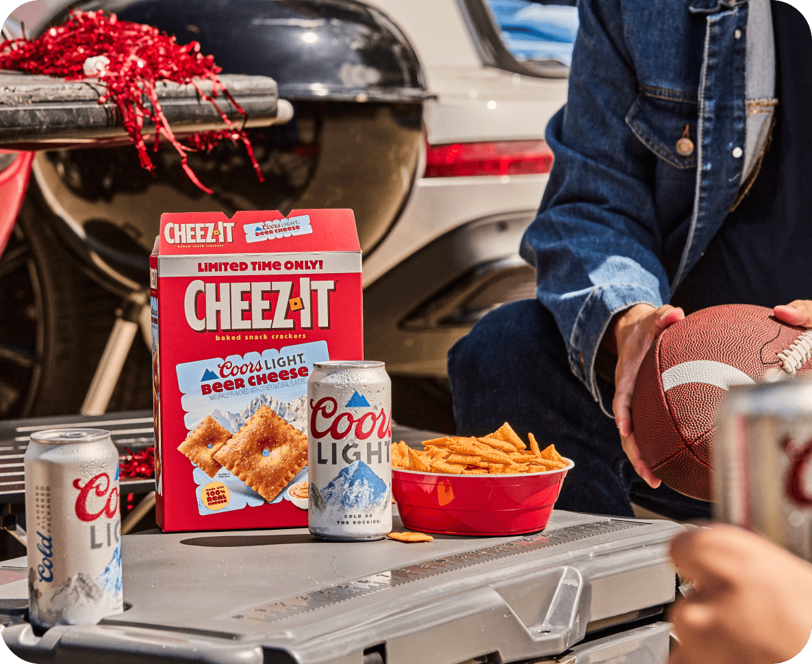 Cheez-It Coors Light package with cans on a cooler at a tailgate party.